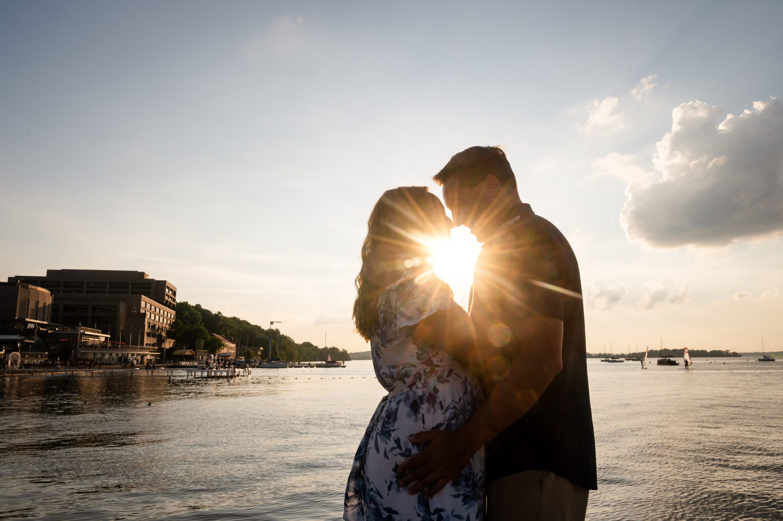 Couple embracing at sunset by Lake Mendota in Madison WI during their engagement session.