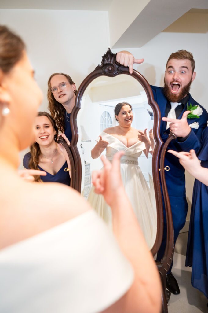 Candid bridal party moment with Marissa laughing in the mirror as her wedding party points and cheers before the ceremony at Chorus Public House.