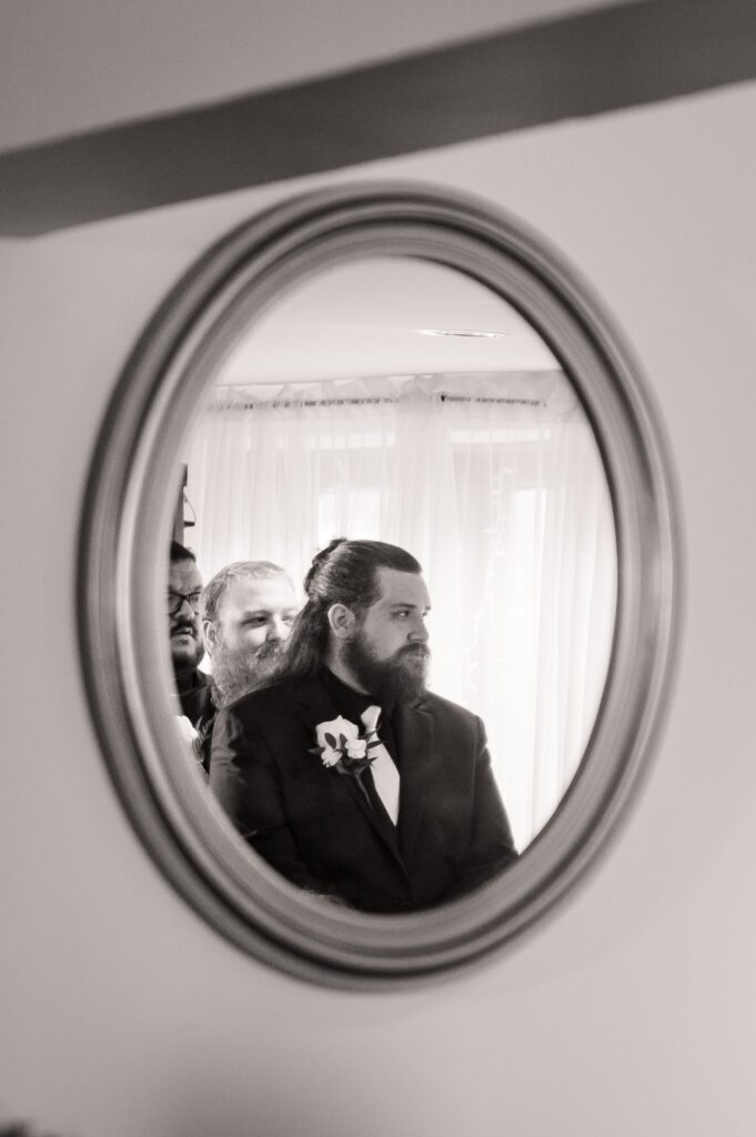 Groom Jared reflected in a wall mirror as he stands at the altar with his groomsmen during the wedding ceremony at Chorus Public House.