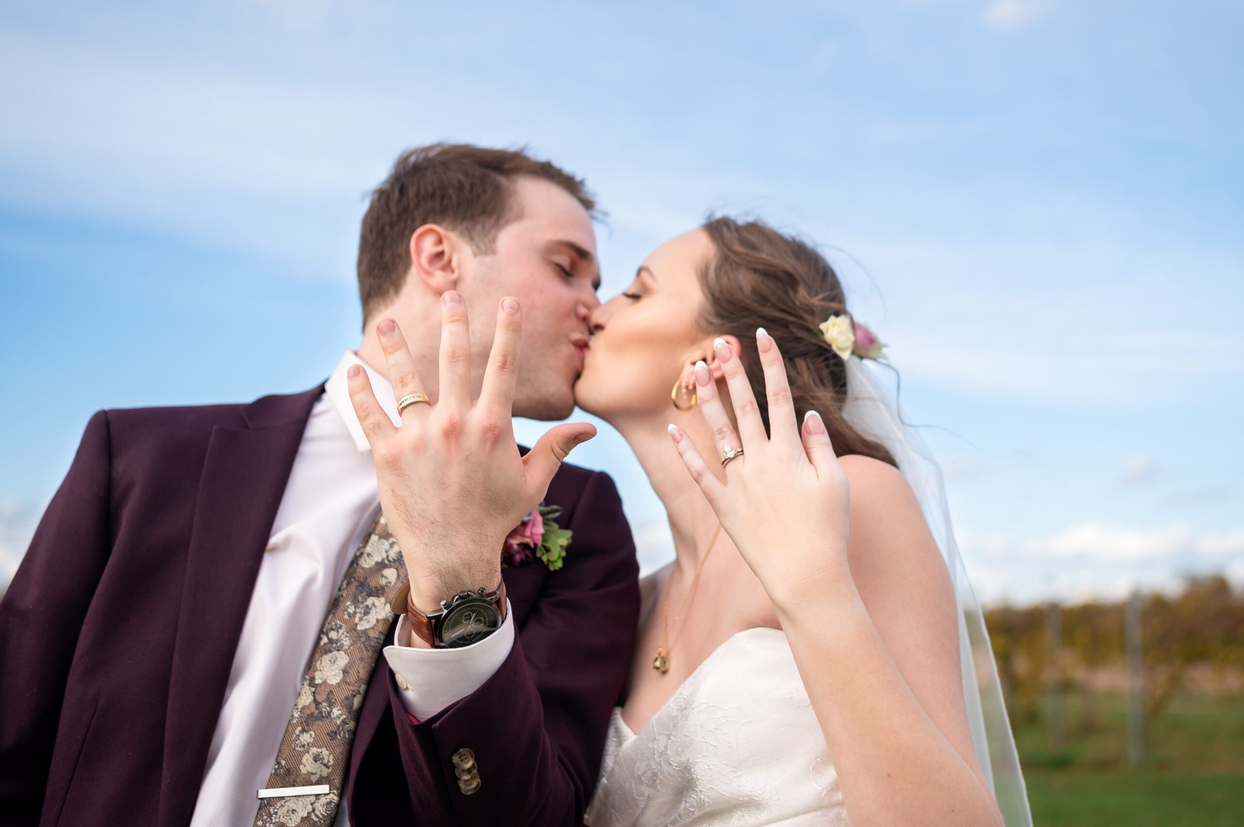 The bride and groom kiss while showing their wedding rings to the camera (how to find your perfect wedding photographer)