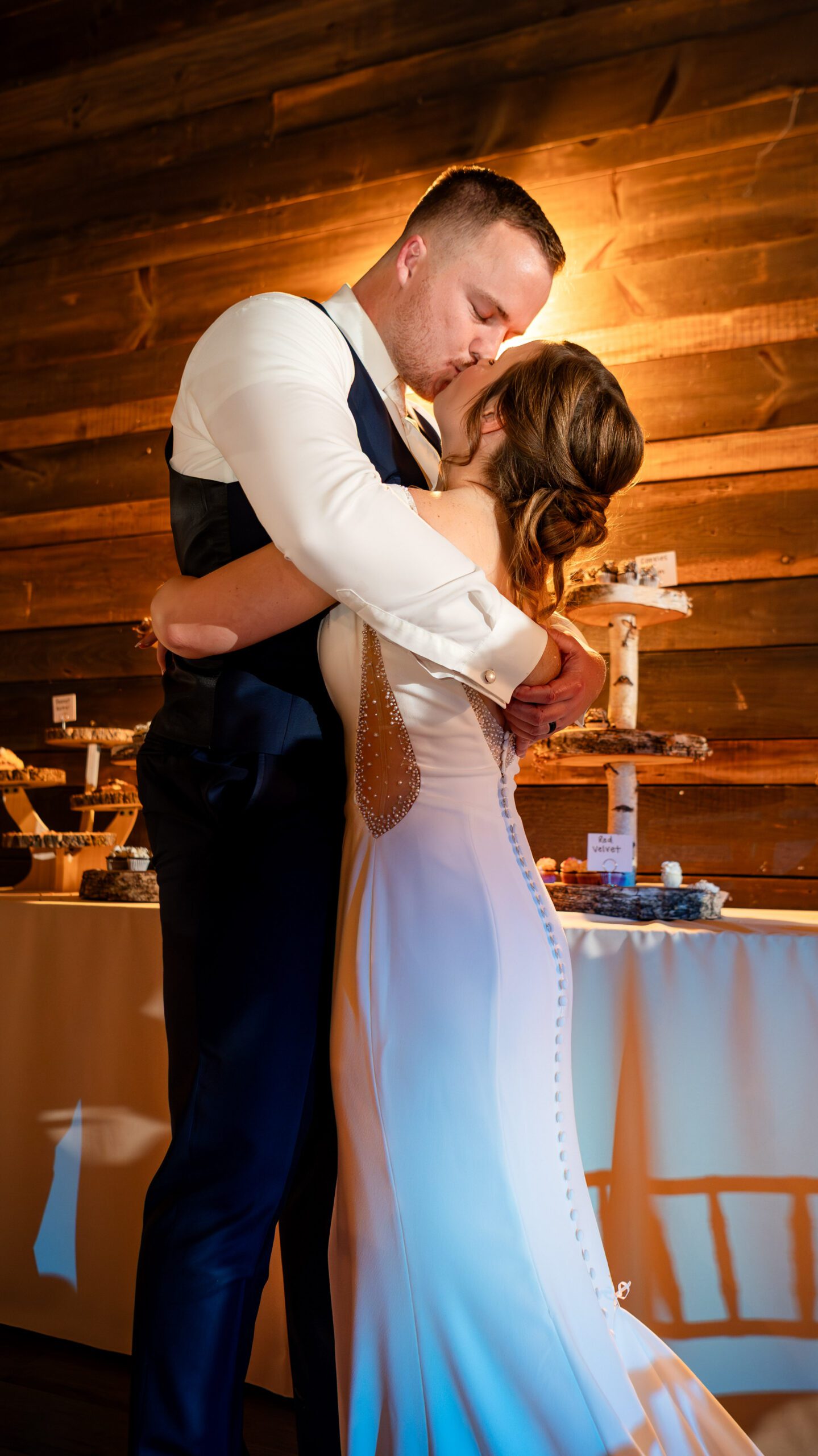 The bride and groom share a kiss after cutting the cake (how to find your perfect wedding photographer)